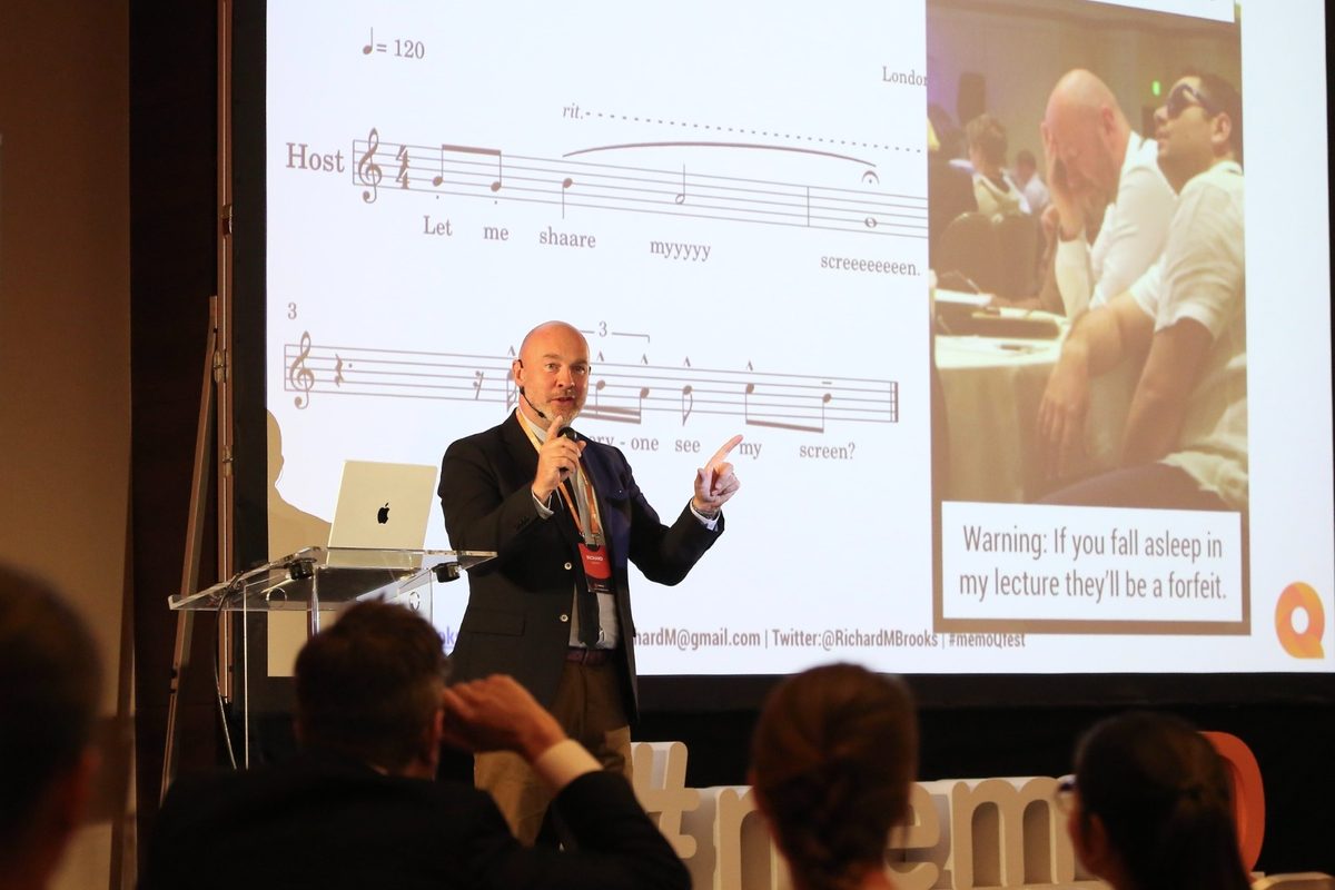 Rich on stage at a conference, performing sheet music titled Let Me Share My Screen